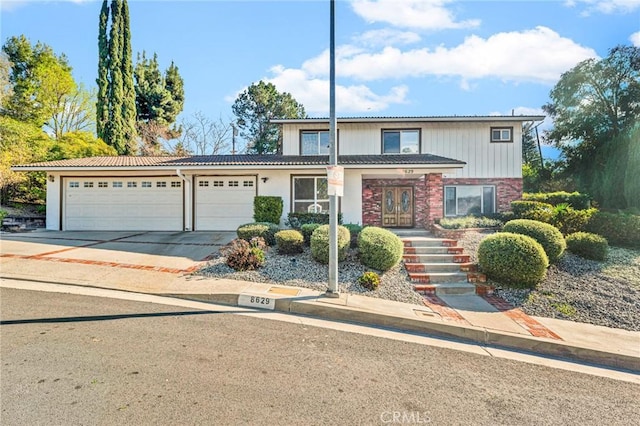 traditional-style house featuring concrete driveway, an attached garage, and a tile roof