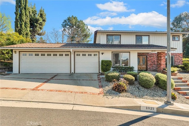 traditional home featuring a tile roof, driveway, brick siding, and an attached garage