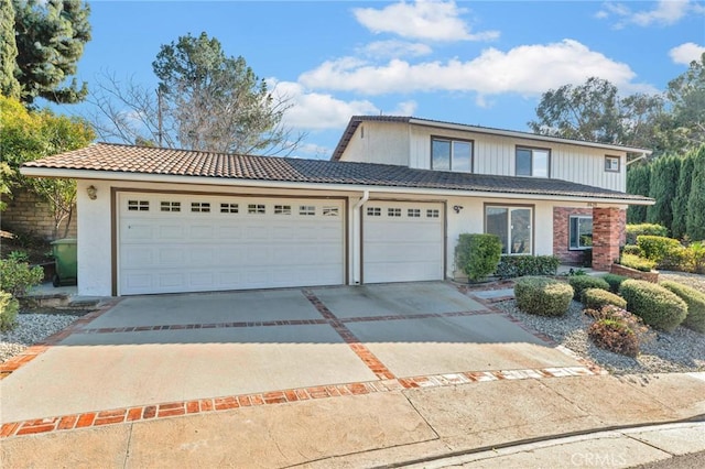 traditional-style home with a garage, driveway, a tile roof, and stucco siding