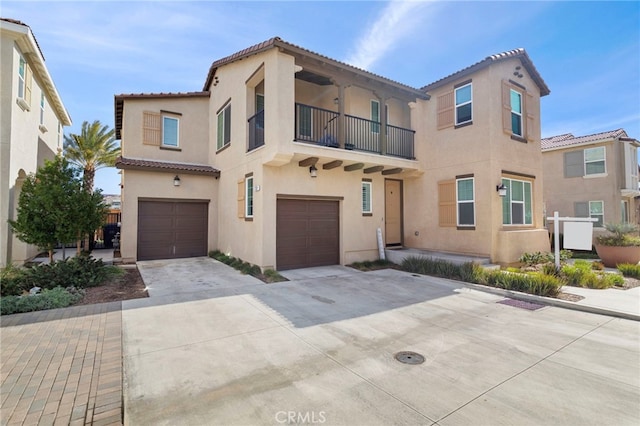 mediterranean / spanish home featuring a garage, a tiled roof, concrete driveway, and stucco siding