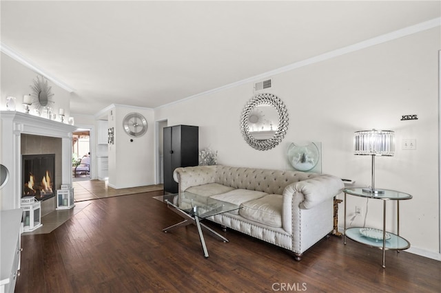 living area featuring baseboards, visible vents, wood finished floors, crown molding, and a fireplace