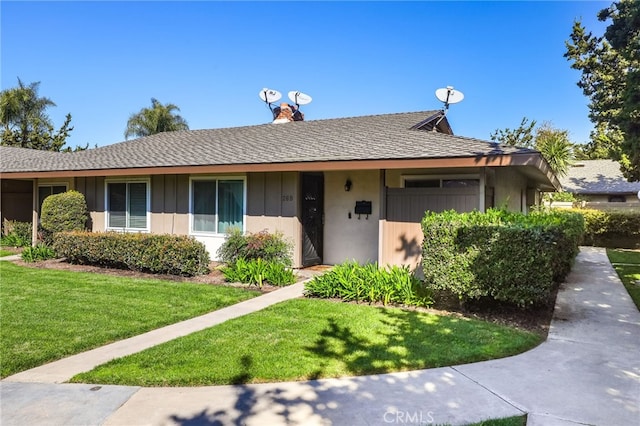 ranch-style home featuring a front lawn, board and batten siding, and roof with shingles