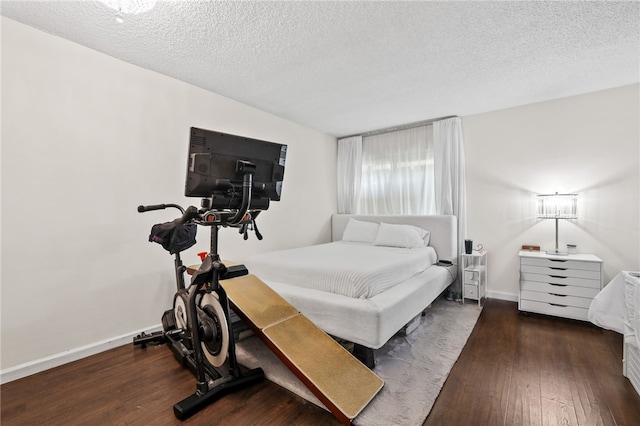 bedroom featuring a textured ceiling, baseboards, and hardwood / wood-style floors