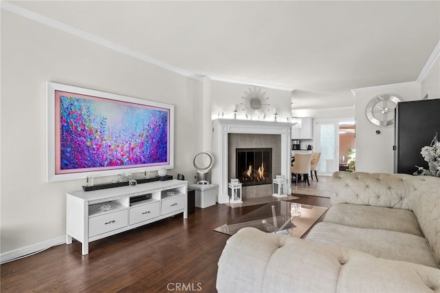 living area featuring crown molding, a fireplace, baseboards, and wood finished floors