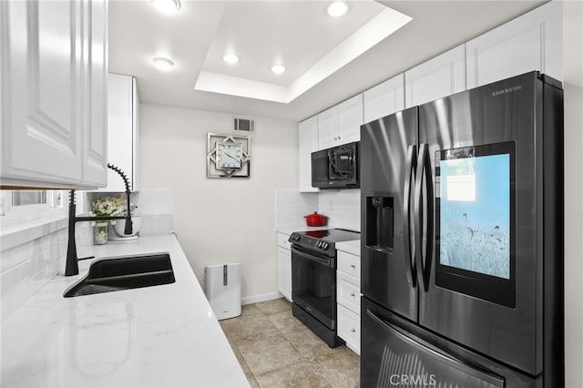 kitchen featuring a sink, visible vents, white cabinets, black appliances, and a raised ceiling