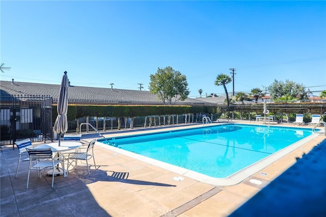 community pool with a patio and fence