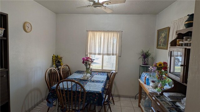 dining room featuring light tile patterned floors, ceiling fan, baseboards, and a textured ceiling