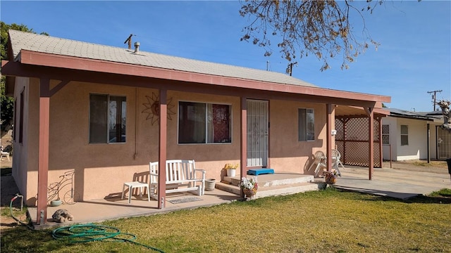 back of house featuring a yard, a patio, and stucco siding