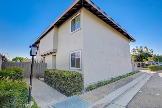 view of side of property featuring stucco siding and fence