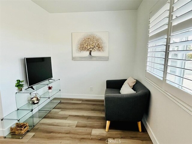 living area with baseboards and wood finished floors
