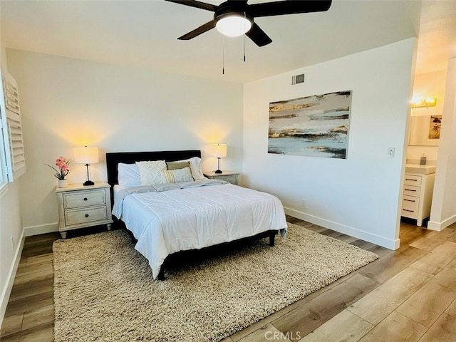 bedroom with wood finished floors, ensuite bath, visible vents, ceiling fan, and baseboards
