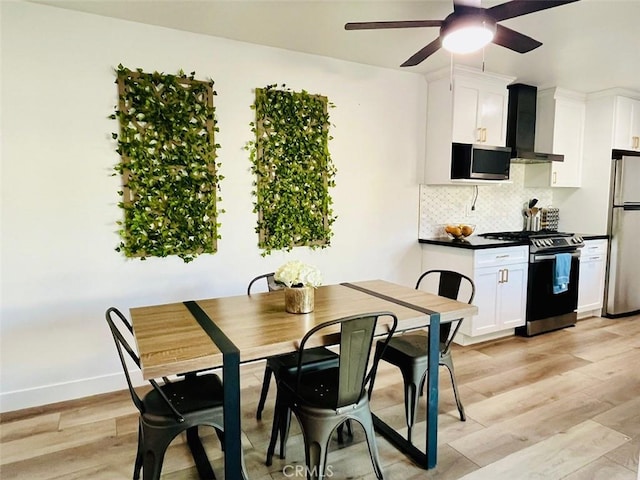 dining space featuring light wood-style floors, baseboards, and a ceiling fan