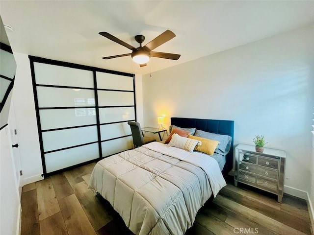 bedroom with ceiling fan, baseboards, and wood finished floors