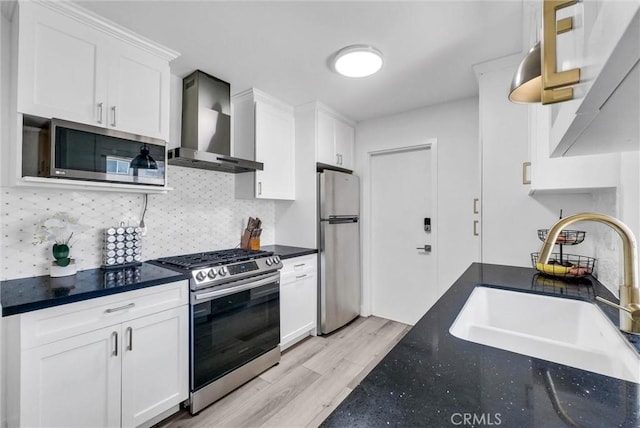 14142 Via Posada Unit 29, Tustin, CA 92780 - kitchen featuring stainless steel appliances, wall chimney range hood, white cabinets, and light wood finished floors