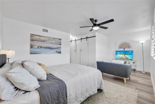 14142 Via Posada Unit 29, Tustin, CA 92780 - bedroom with a barn door, wood finished floors, a ceiling fan, and baseboards