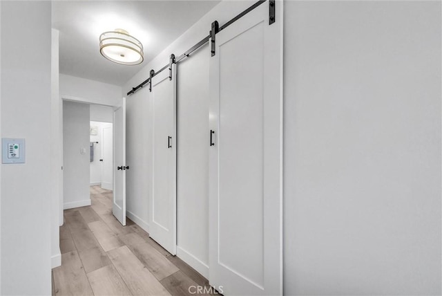 14142 Via Posada Unit 29, Tustin, CA 92780 - hallway with a barn door, light wood-style flooring, and baseboards