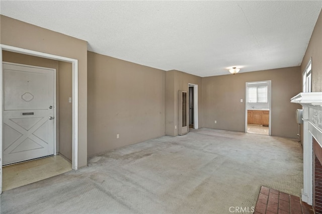847 W 25th St, San Bernardino, CA 92405 - unfurnished living room featuring a fireplace with flush hearth, light colored carpet, and a textured ceiling