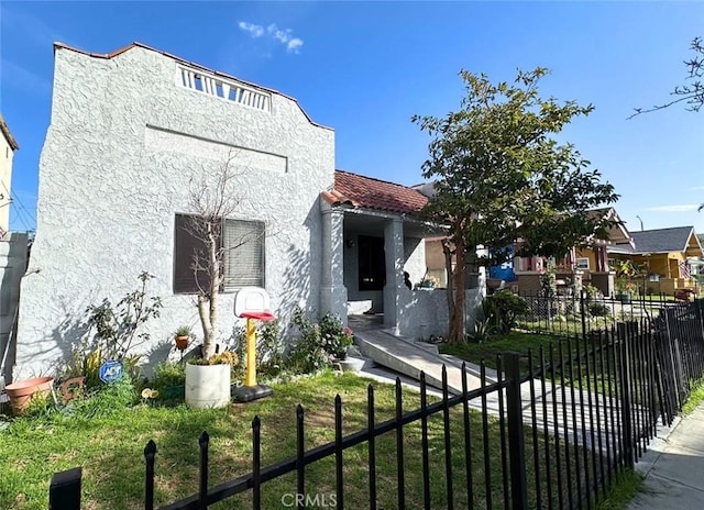 view of front of property with a fenced front yard, a tiled roof, and stucco siding