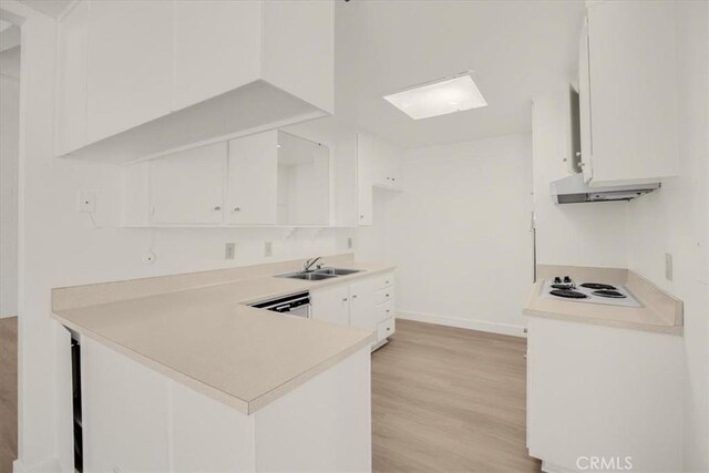 kitchen featuring light countertops, a sink, white cabinetry, and under cabinet range hood