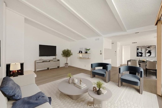 living area with visible vents, lofted ceiling with beams, a textured ceiling, and wood finished floors