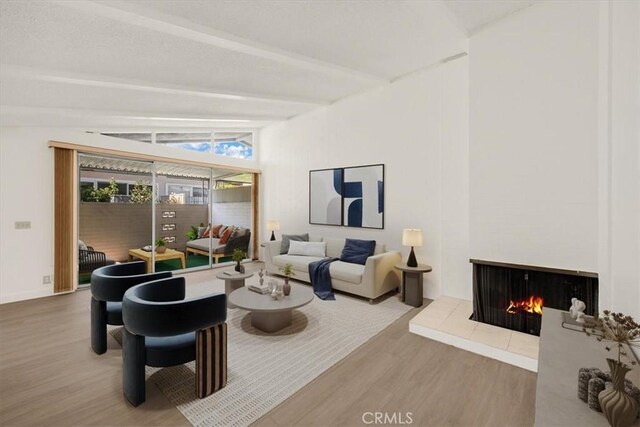 living room featuring lofted ceiling with beams, a fireplace, and wood finished floors