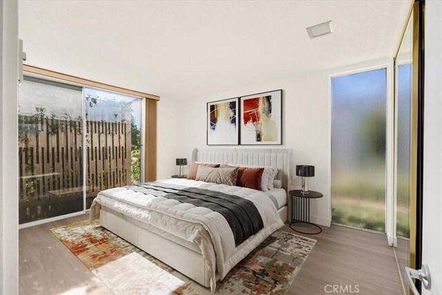 bedroom with a wall of windows and wood finished floors