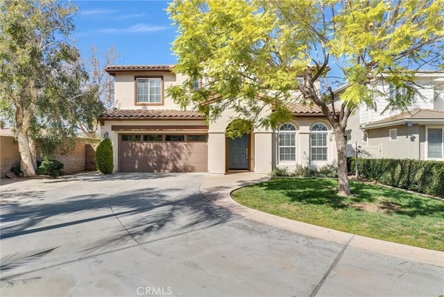 mediterranean / spanish home featuring an attached garage, fence, a tile roof, driveway, and stucco siding