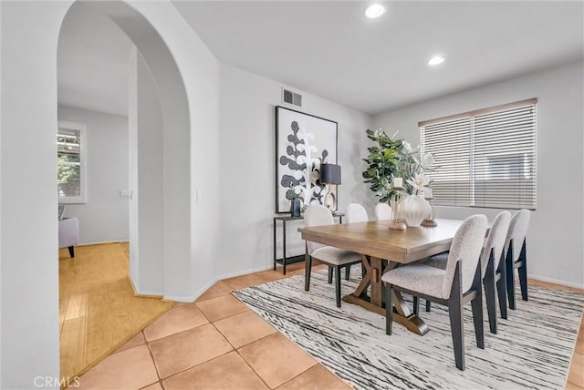 dining room featuring arched walkways, light tile patterned floors, recessed lighting, visible vents, and baseboards