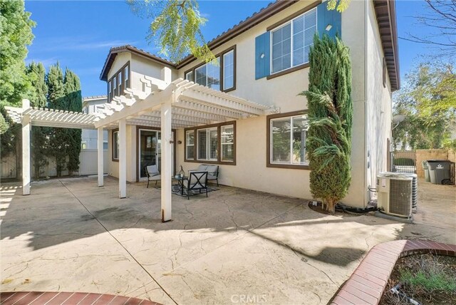 rear view of property with stucco siding, fence, central AC unit, and a pergola