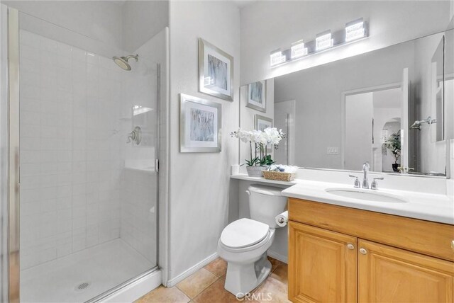 bathroom featuring toilet, vanity, baseboards, a shower stall, and tile patterned floors