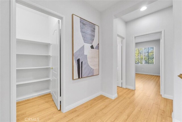 hall with recessed lighting, baseboards, and light wood finished floors