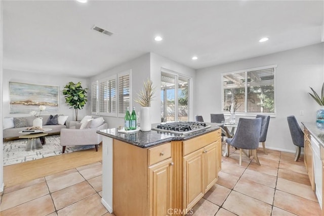 kitchen featuring visible vents, stainless steel gas stovetop, open floor plan, light tile patterned flooring, and dark stone countertops