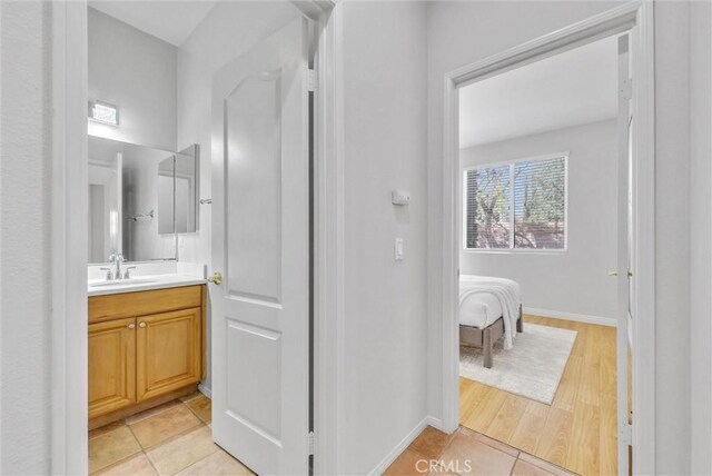 ensuite bathroom with baseboards, ensuite bath, vanity, and tile patterned floors