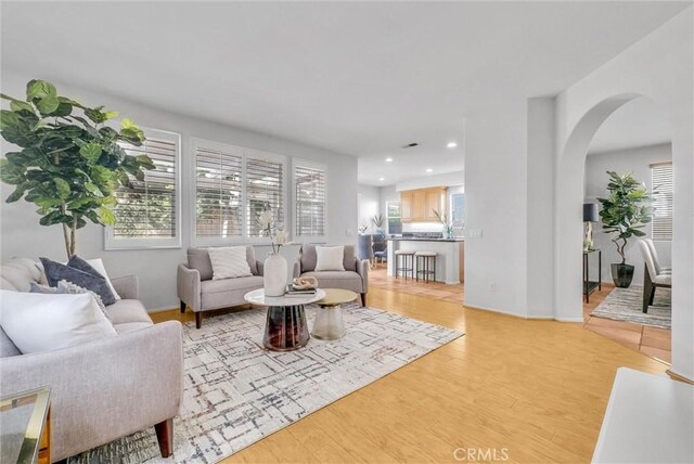 living room featuring arched walkways, light wood-style flooring, and recessed lighting