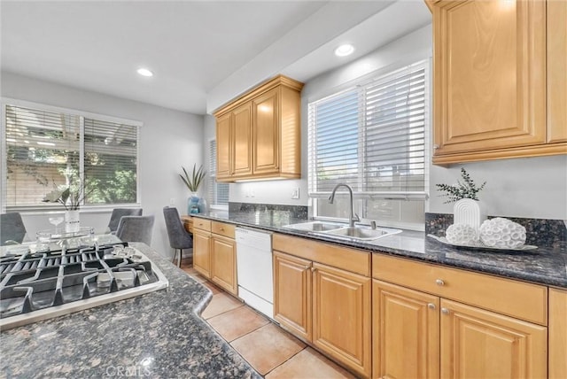 kitchen featuring dark stone counters, gas stovetop, white dishwasher, and a sink