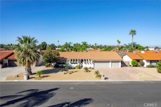 view of front of home featuring an attached garage, concrete driveway, and a tiled roof