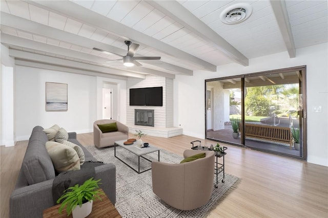 living room featuring a brick fireplace, visible vents, light wood finished floors, and baseboards