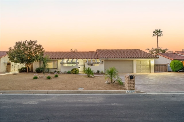 view of front of property featuring a garage, fence, driveway, a tiled roof, and stucco siding