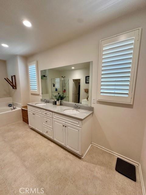 full bathroom with double vanity, a stall shower, baseboards, a bath, and a sink