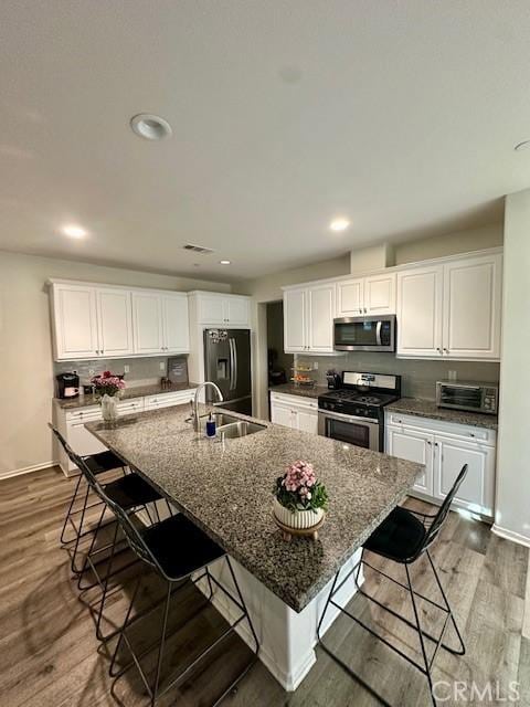 kitchen featuring appliances with stainless steel finishes, white cabinetry, an island with sink, and a breakfast bar area