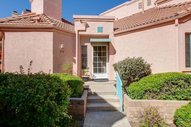 property entrance with a tile roof and stucco siding