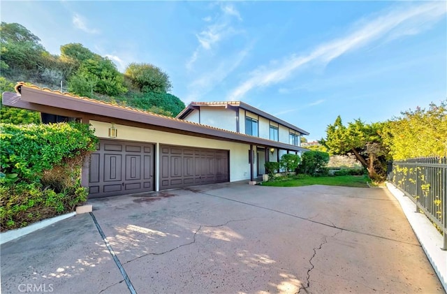 view of front of house featuring a garage, concrete driveway, fence, and stucco siding