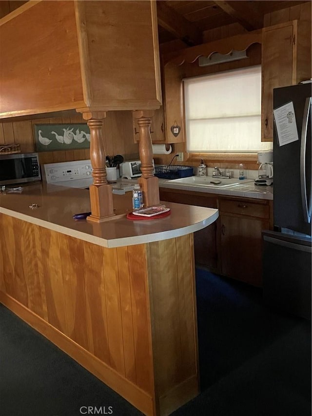 kitchen featuring stainless steel microwave, brown cabinets, a sink, and freestanding refrigerator