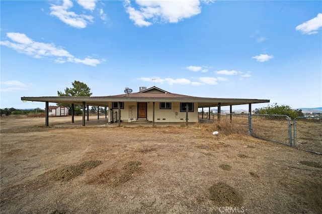 farmhouse featuring an attached carport, a rural view, fence, and driveway