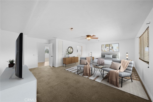 living room featuring a wealth of natural light, baseboards, a ceiling fan, and light colored carpet