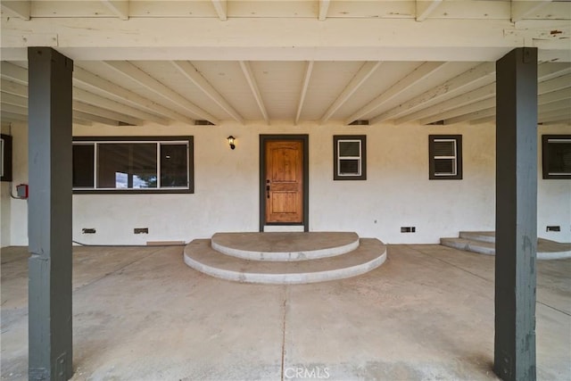 entrance to property featuring crawl space, a patio area, and stucco siding