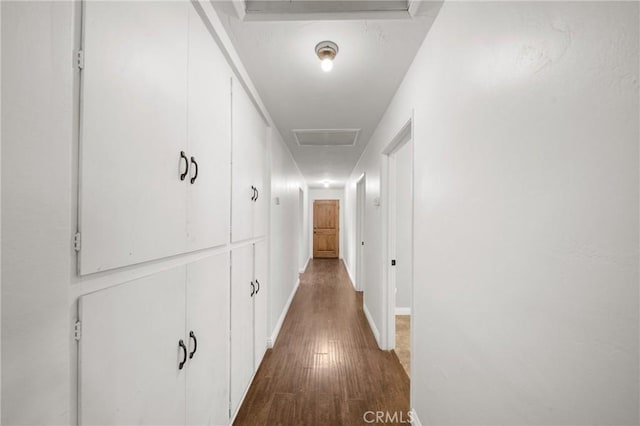 hall featuring dark wood-style floors, attic access, and baseboards