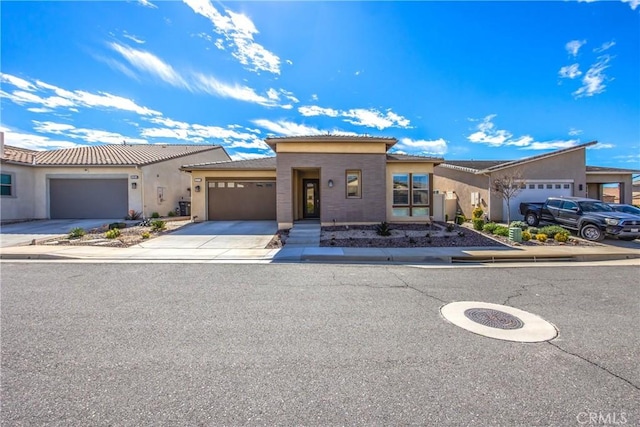 view of front of house featuring driveway, an attached garage, a tile roof, and stucco siding