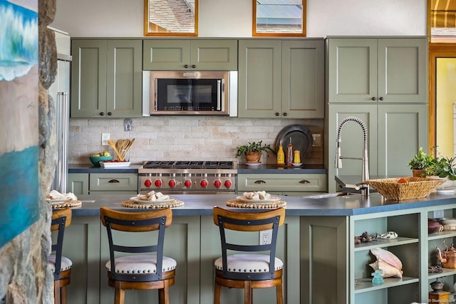 kitchen with open shelves, stainless steel appliances, backsplash, a sink, and green cabinetry