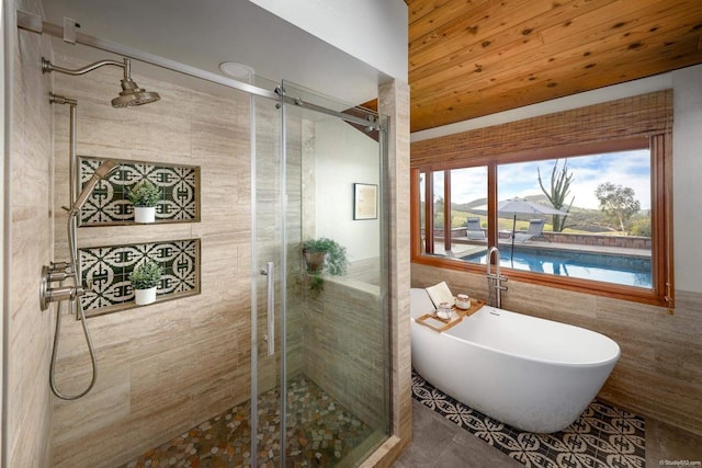 bathroom featuring a stall shower, a freestanding tub, tile patterned flooring, and tile walls